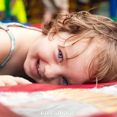 Foto profissional de fotografia infantil Pirralhitus, menina sorrindo deitada em festa de aniversário no Rio de Janeiro